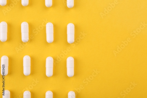 Many vitamin capsules on orange background, flat lay. Space for text