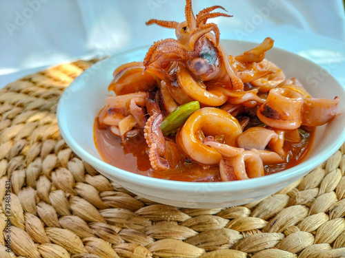 Seafood deliciouse - Cumi Asam Manis or Sweet and Sour Saute Squid with green pete served on white bowl above the Table. Selective focus.
 photo