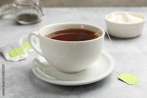 Tea bags and cup of hot beverage on light table  closeup