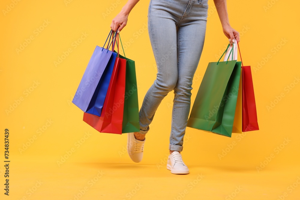 Woman with shopping bags on yellow background, closeup