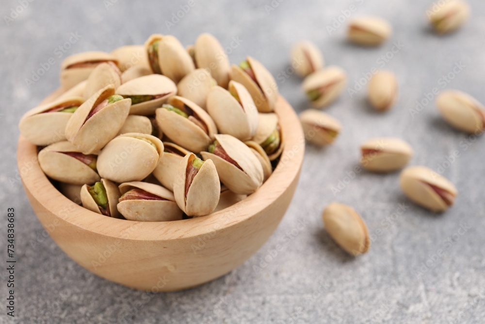 Delicious pistachios in bowl on grey textured table Delicious pistachios in bowl on grey textured table