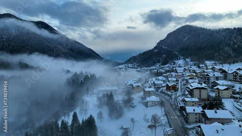 Aerial drone view of foggy Town in dolomites in Italty. Italian mountain town Berguzzo in alps. Adamello Brenta park in dolomites Trentino. Cloudy winter day in small town in the Italian mountains.  photo