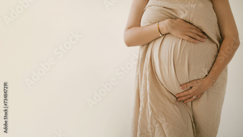 Young pregnant woman hugging her belly on white background.
