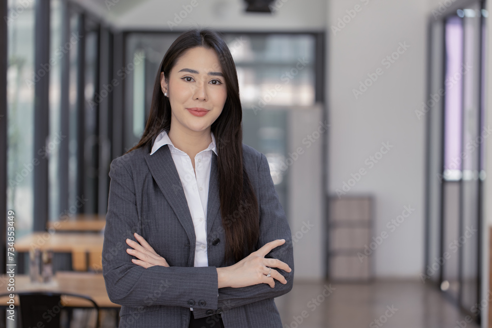 Happy asian young businesswoman arms crossed standing in office working space. Happy asian young businesswoman arms crossed standing in office working space.