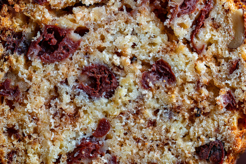 Close up of sliced muffin with red cherries and walnuts, macro. Homemade delicious muffins surface background or texture