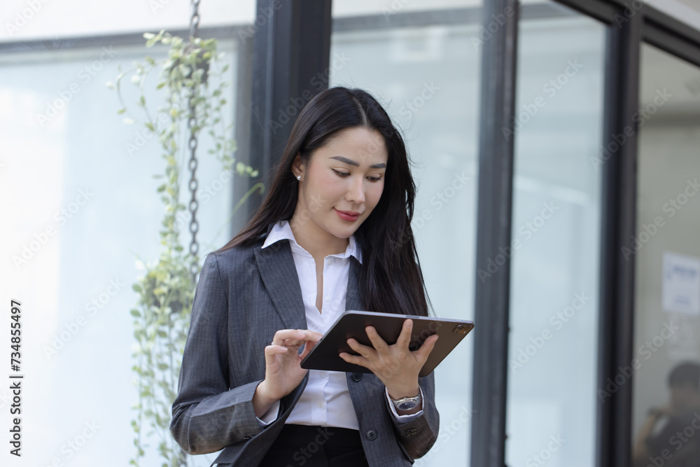 Happy asian young businesswoman using digital tablet standing in office office working space. Happy asian young businesswoman using digital tablet standing in office office working space.