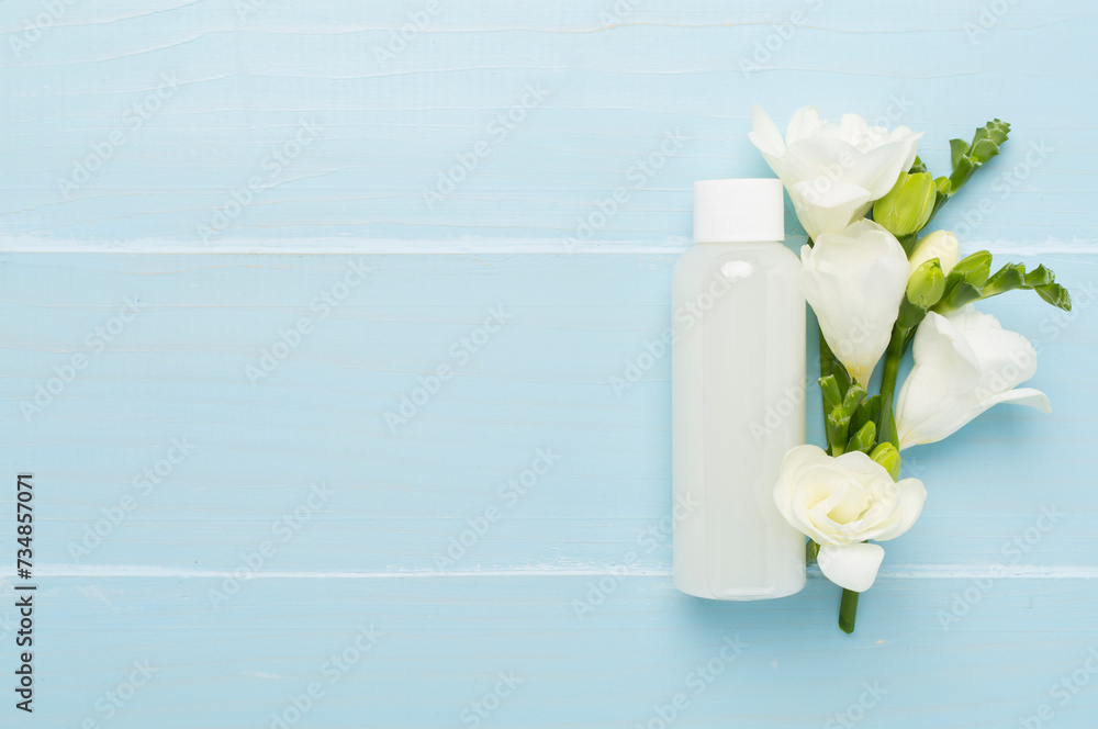 Cosmetic bottle with freesia flowers on wooden background, top view Cosmetic bottle with freesia flowers on wooden background, top view
