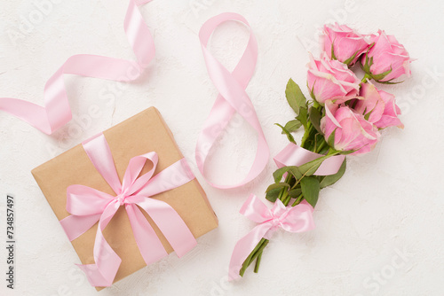 Composition with pink roses, gift box and eight made of ribbon on concrete background, top view. Women's day concept