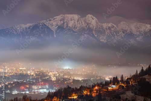 Night scenery of the Polish town of Zakopane. Snow-covered High Tatras are visible in the background. photo