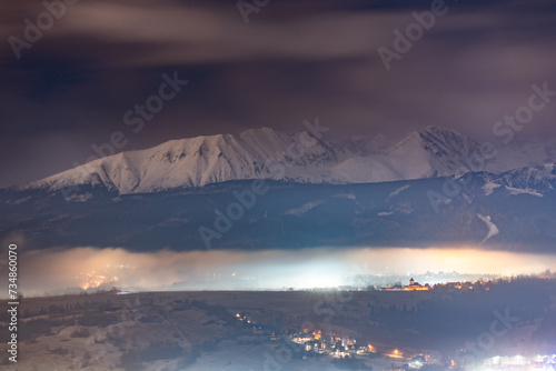 Night scenery of the Polish town of Zakopane. Snow-covered High Tatras are visible in the background. photo