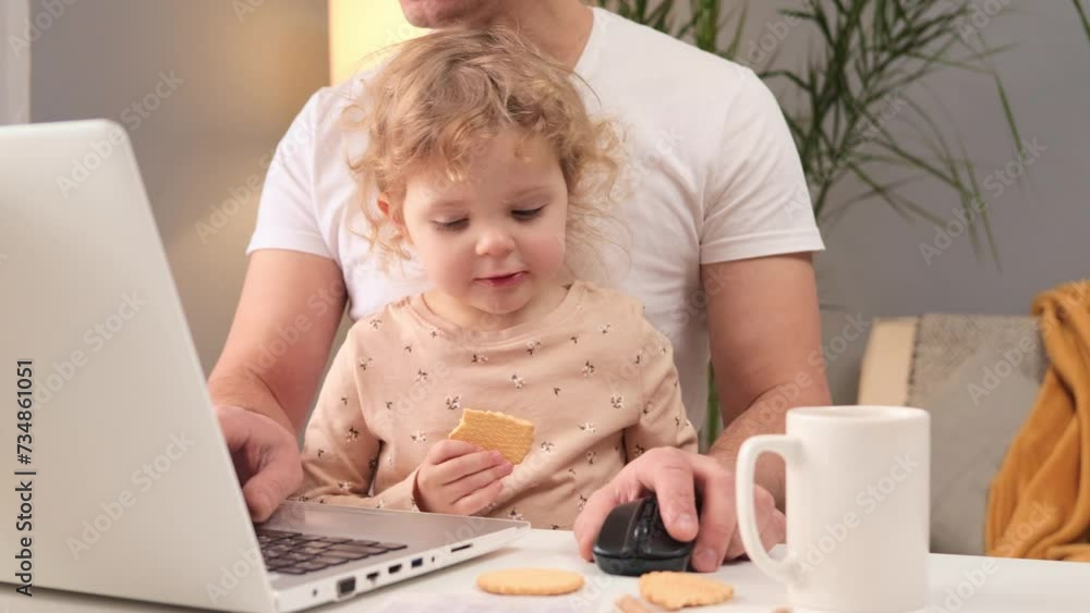 Cute blonde wavy haired little baby girl sitting with working on laptop man at table at home charming child eating cookie father typing on keyboard doing his remote job Cute blonde wavy haired little baby girl sitting with working on laptop man at table at home charming child eating cookie father typing on keyboard doing his remote job