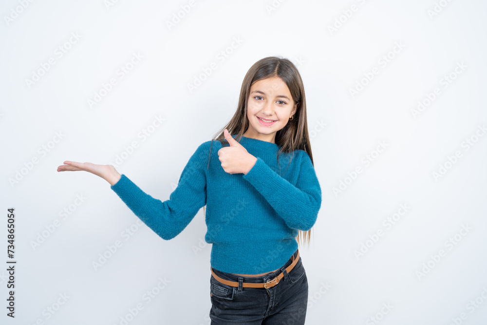 Young beautiful teen girl wearing blue T-shirt Showing palm hand and doing ok gesture with thumbs up, smiling happy and cheerful. Young beautiful teen girl wearing blue T-shirt Showing palm hand and doing ok gesture with thumbs up, smiling happy and cheerful.