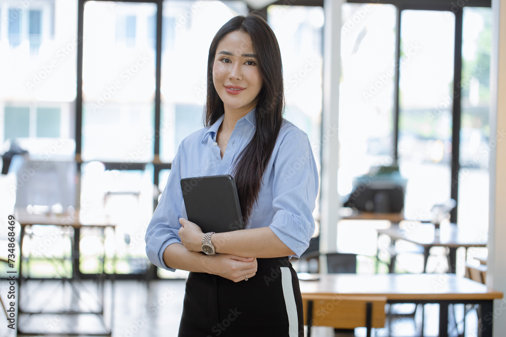 Happy asian young businesswoman holding a digital tablet standing in office office working space. Happy asian young businesswoman holding a digital tablet standing in office office working space.