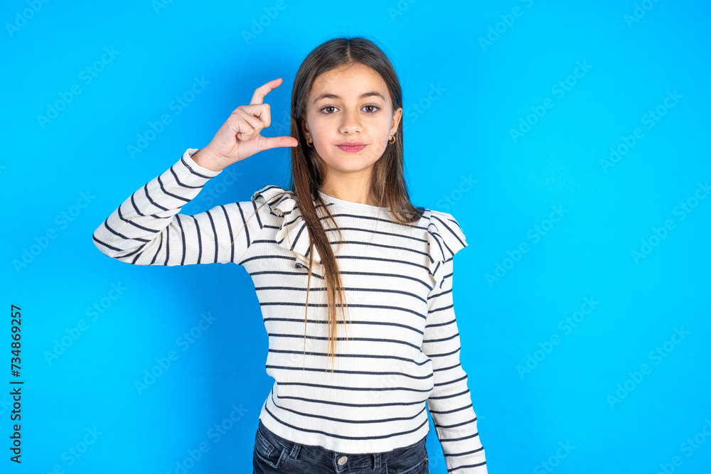Fototapeta premium Young beautiful teen girl wearing striped T-shirt smiling and confident gesturing with hand doing small size sign with fingers looking and the camera. Measure concept