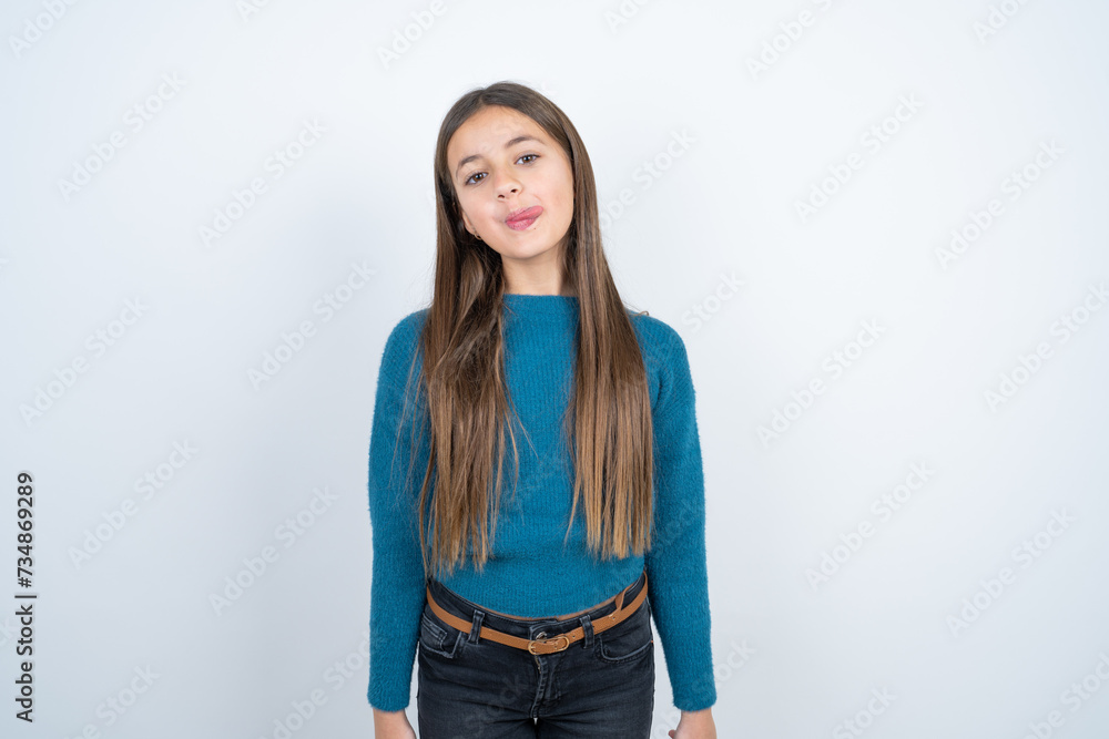 Young beautiful teen girl wearing blue T-shirt sticking tongue out happy with funny expression. Emotion concept. Young beautiful teen girl wearing blue T-shirt sticking tongue out happy with funny expression. Emotion concept.