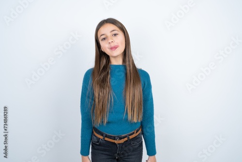Young beautiful teen girl wearing blue T-shirt sticking tongue out happy with funny expression. Emotion concept.