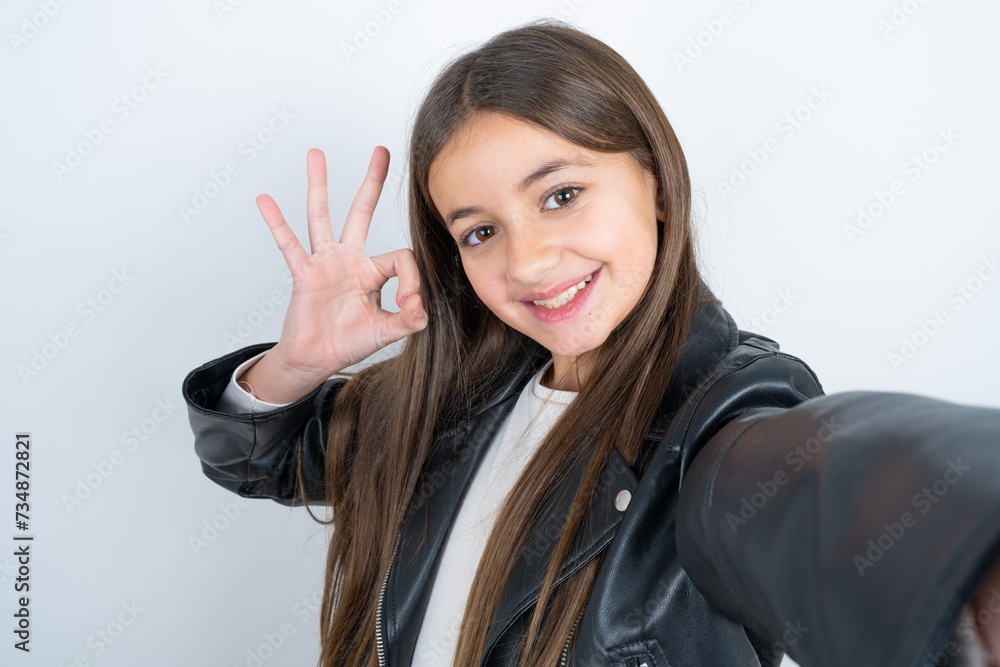 Portrait of pretty cheerful Young beautiful teen girl wearing biker jacket make selfie show okey symbol Portrait of pretty cheerful Young beautiful teen girl wearing biker jacket make selfie show okey symbol