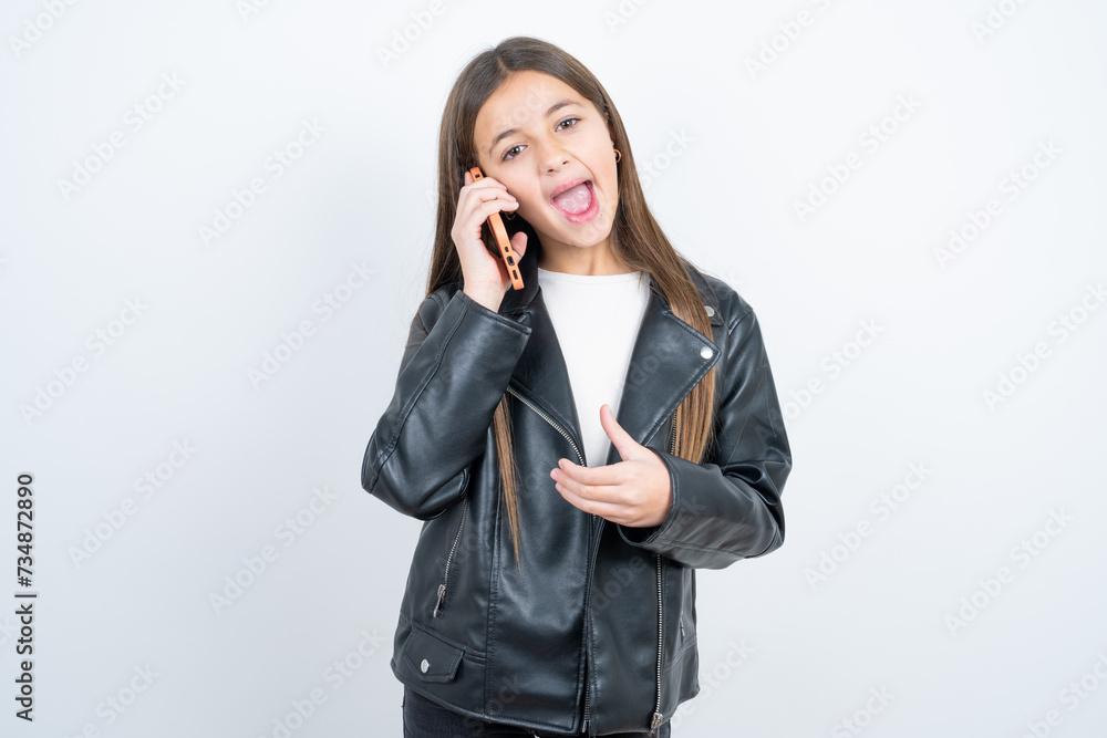 Pleasant looking happy Young beautiful teen girl wearing biker jacket has nice telephone conversation and looks aside, has nice mood and smiles positively while talks via cell phone Pleasant looking happy Young beautiful teen girl wearing biker jacket has nice telephone conversation and looks aside, has nice mood and smiles positively while talks via cell phone