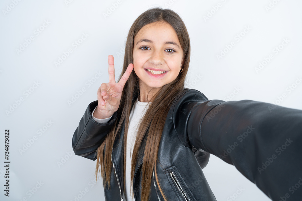 Positive Young beautiful teen girl wearing biker jacket take selfie make v-sign Positive Young beautiful teen girl wearing biker jacket take selfie make v-sign