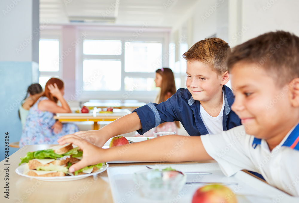 Smiling male students sharing sandwiches in school Smiling male students sharing sandwiches in school