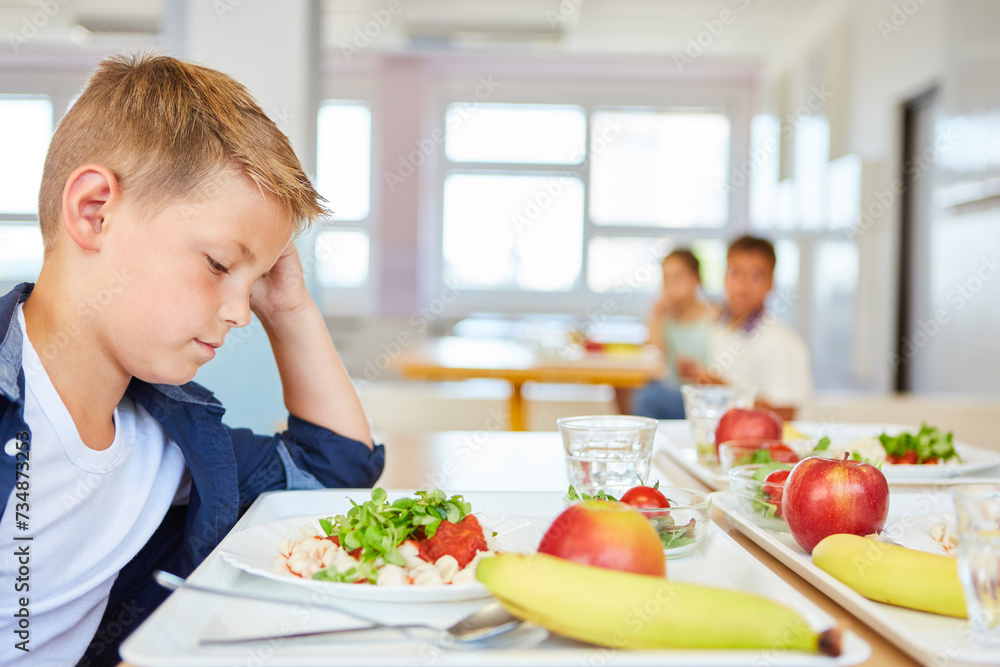 Worried blond boy staring at food plate in school cafeteria Worried blond boy staring at food plate in school cafeteria