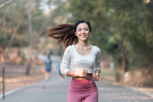 A fit woman enjoys a healthy jog in a park filled with summery green © phaitoon