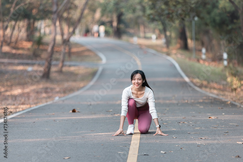 A fit woman enjoys a healthy jog in a park filled with summery green © phaitoon