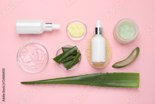 Flat lay composition with cosmetic products and cut aloe leaves on pink background