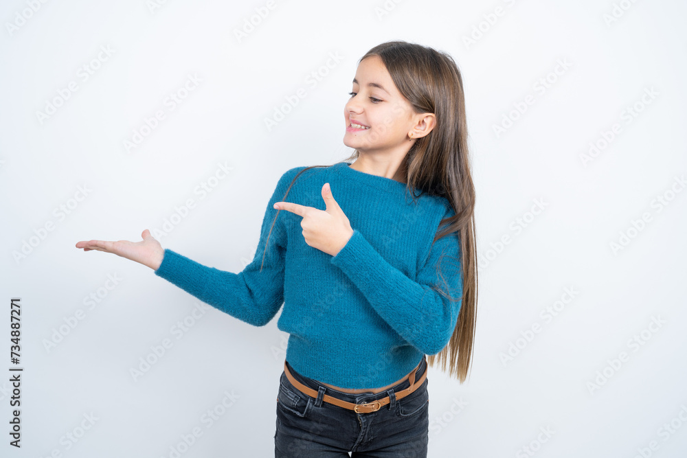 Positive beautiful kid girl wearing blue sweater promoter point index finger copyspace hold hand demonstrate offer ads promo Positive beautiful kid girl wearing blue sweater promoter point index finger copyspace hold hand demonstrate offer ads promo