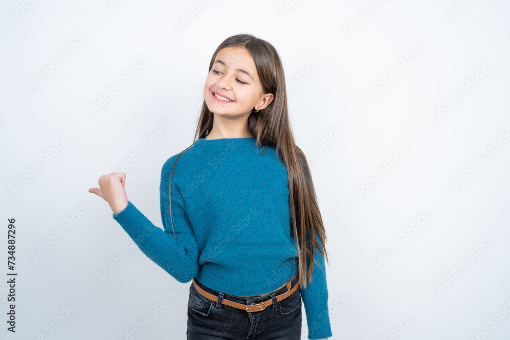 Charming beautiful kid girl wearing blue sweater looking at copy space having advertisements Charming beautiful kid girl wearing blue sweater looking at copy space having advertisements