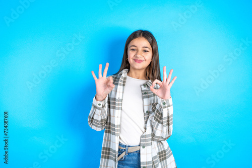 Valokuva Beautiful kid girl wearing plaid shirt showing both hands with fingers in OK sign