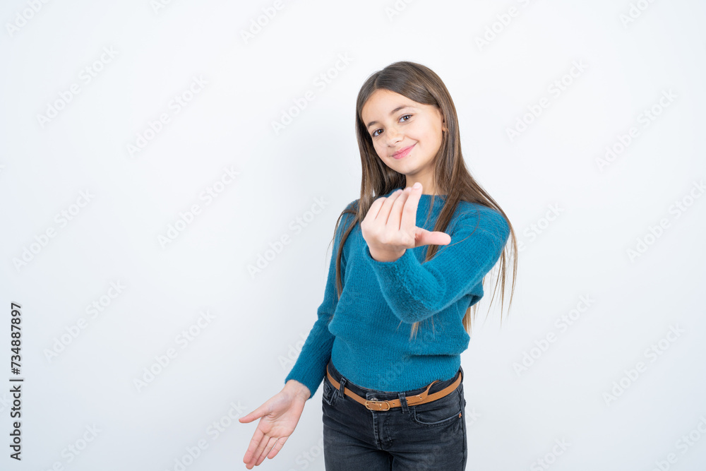 beautiful kid girl wearing blue sweater inviting to come with hand. Happy that you came beautiful kid girl wearing blue sweater inviting to come with hand. Happy that you came