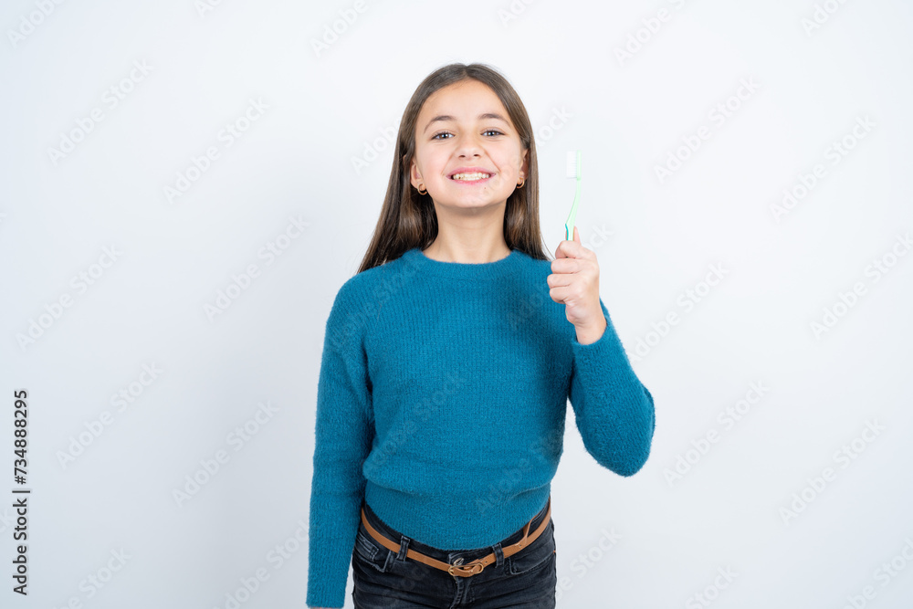 Desperate beautiful kid girl wearing blue sweater trembles and feels cold, hugs oneself to warm up or feels scared notices something terrifying.