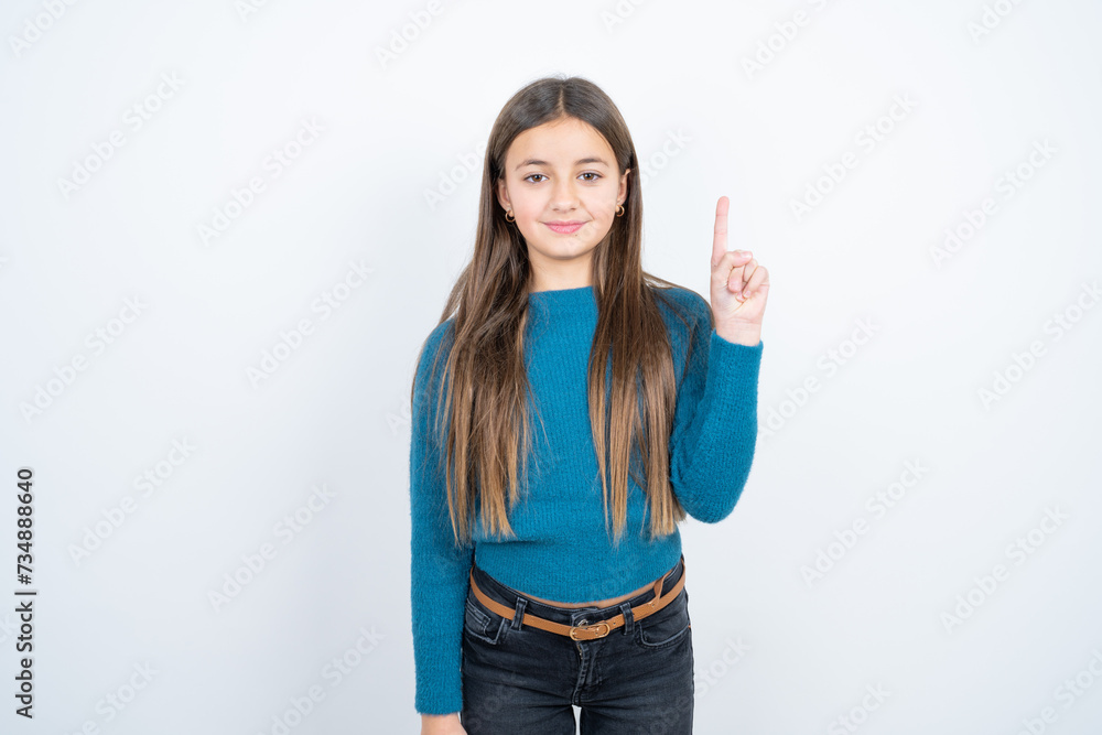 beautiful kid girl wearing blue sweater showing and pointing up with finger number one while smiling confident and happy. beautiful kid girl wearing blue sweater showing and pointing up with finger number one while smiling confident and happy.