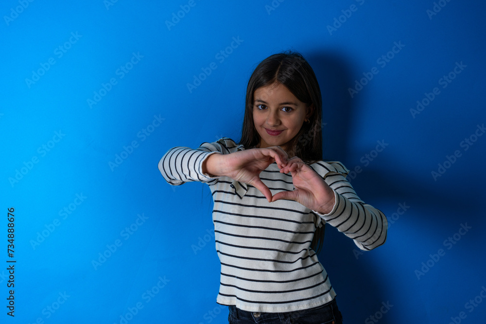 beautiful kid girl wearing striped T -shirt smiling in love doing heart symbol shape with hands. Romantic concept. beautiful kid girl wearing striped T -shirt smiling in love doing heart symbol shape with hands. Romantic concept.