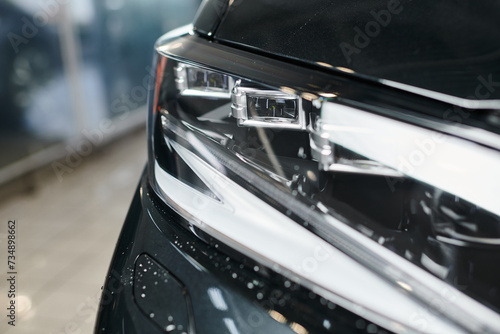 object photo of black modern automobile with its headlights in garage during cleaning service photo