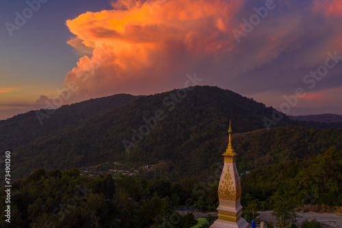 aerial view scenery sunset above pagoda of Doi Thepnimit temple on the highest of Patong mountain..The lights twinkle at twilight background..Scene of Colorful romantic sky sunset, beautiful pagoda.