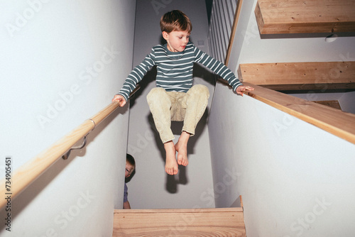 Low angle view of boy balancing mid-air between staircase while playing at home photo