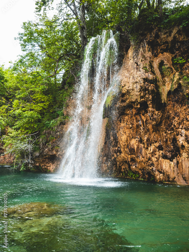 Fototapeta premium Beautiful waterfall surrounded by lush greenery in Plitvice Lakes National Park. Croatia