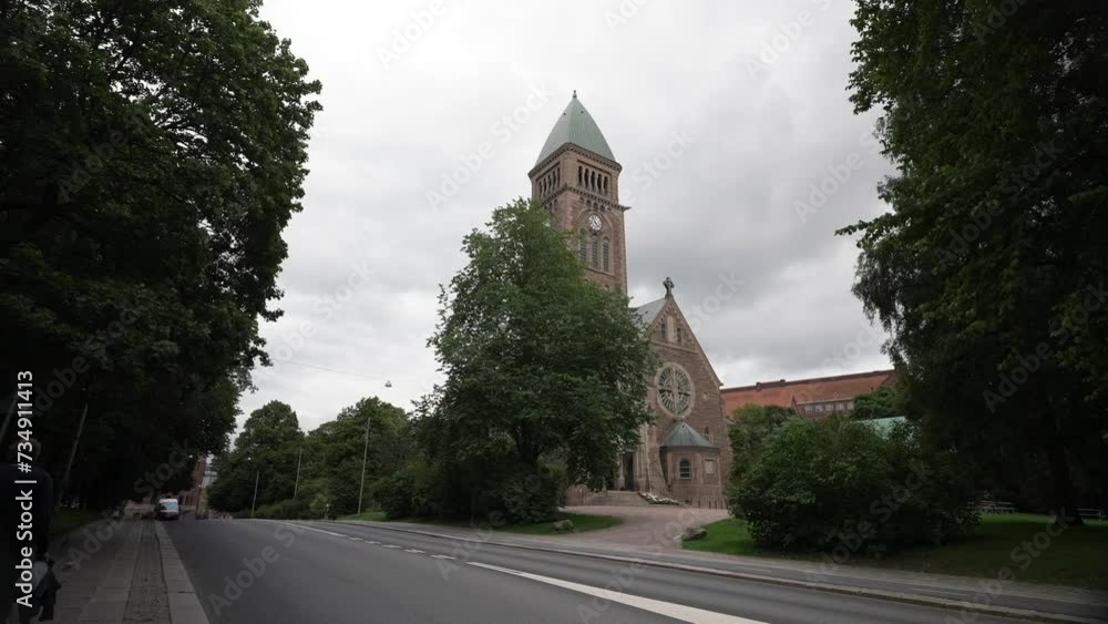 A view of the Vasa church in Gothenburg, Sweden, The Vasa Church tower with a cloudy blue sky in the background, Neo-Romanesque style, Scandinavia, Europe, beautiful, through trees on a autumn day A view of the Vasa church in Gothenburg, Sweden, The Vasa Church tower with a cloudy blue sky in the background, Neo-Romanesque style, Scandinavia, Europe, beautiful, through trees on a autumn day