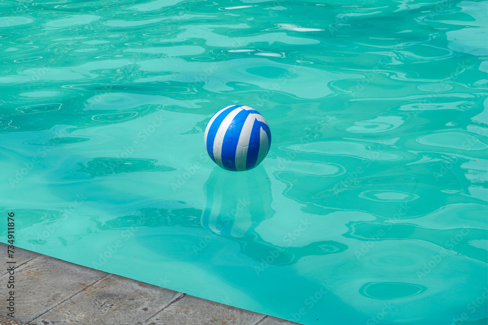 Blue and white plastic ball floating in the swimming pool