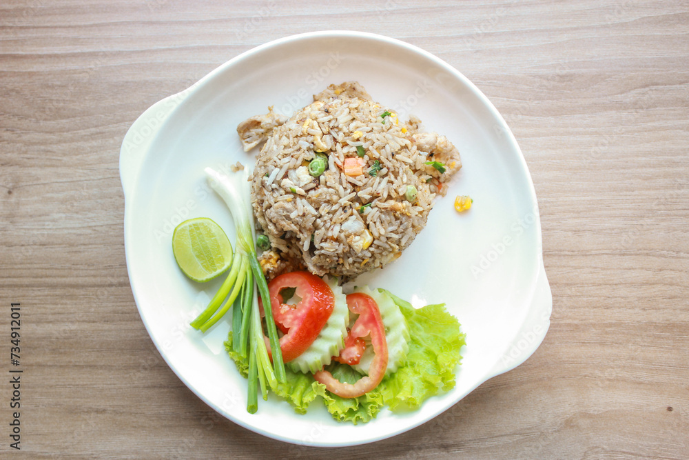 Pork fried rice served in a restaurant with wooden floor tables with tomatoes, cucumbers, scallions, fried rice, delicious food made from steamed rice, top view Pork fried rice served in a restaurant with wooden floor tables with tomatoes, cucumbers, scallions, fried rice, delicious food made from steamed rice, top view