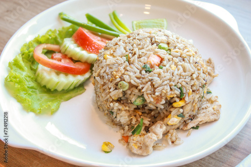 Pork fried rice served in a restaurant with wooden floor tables with tomatoes, cucumbers, scallions, fried rice, delicious food made from steamed rice.