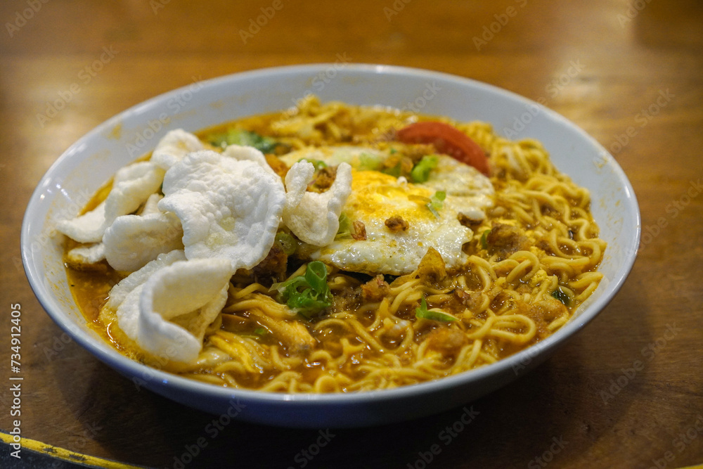Javanese godok noodles topped with egg, shredded chicken, crackers Javanese godok noodles topped with egg, shredded chicken, crackers