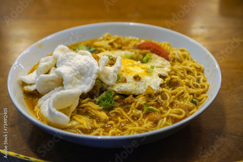 Javanese godok noodles topped with egg, shredded chicken, crackers