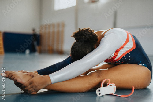Teenage girl practices stretching exercise while sitting in gym photo