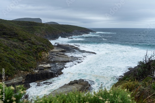 waves breaking on rocks in on the coast by the sea in tasmania australia in summer © William