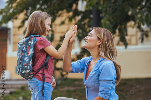 Happy family preparing for school. Little girl with mother. Mother saying goodbye to her daughter at school. Beginning of lessons. First day of fall.