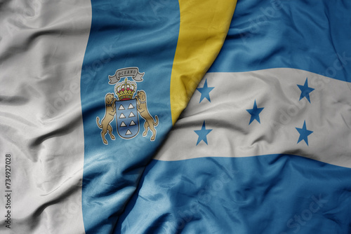 big waving national colorful flag of honduras and national flag of canary islands .