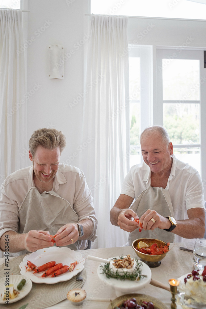 Two men deveining prawns at dinner table Two men deveining prawns at dinner table